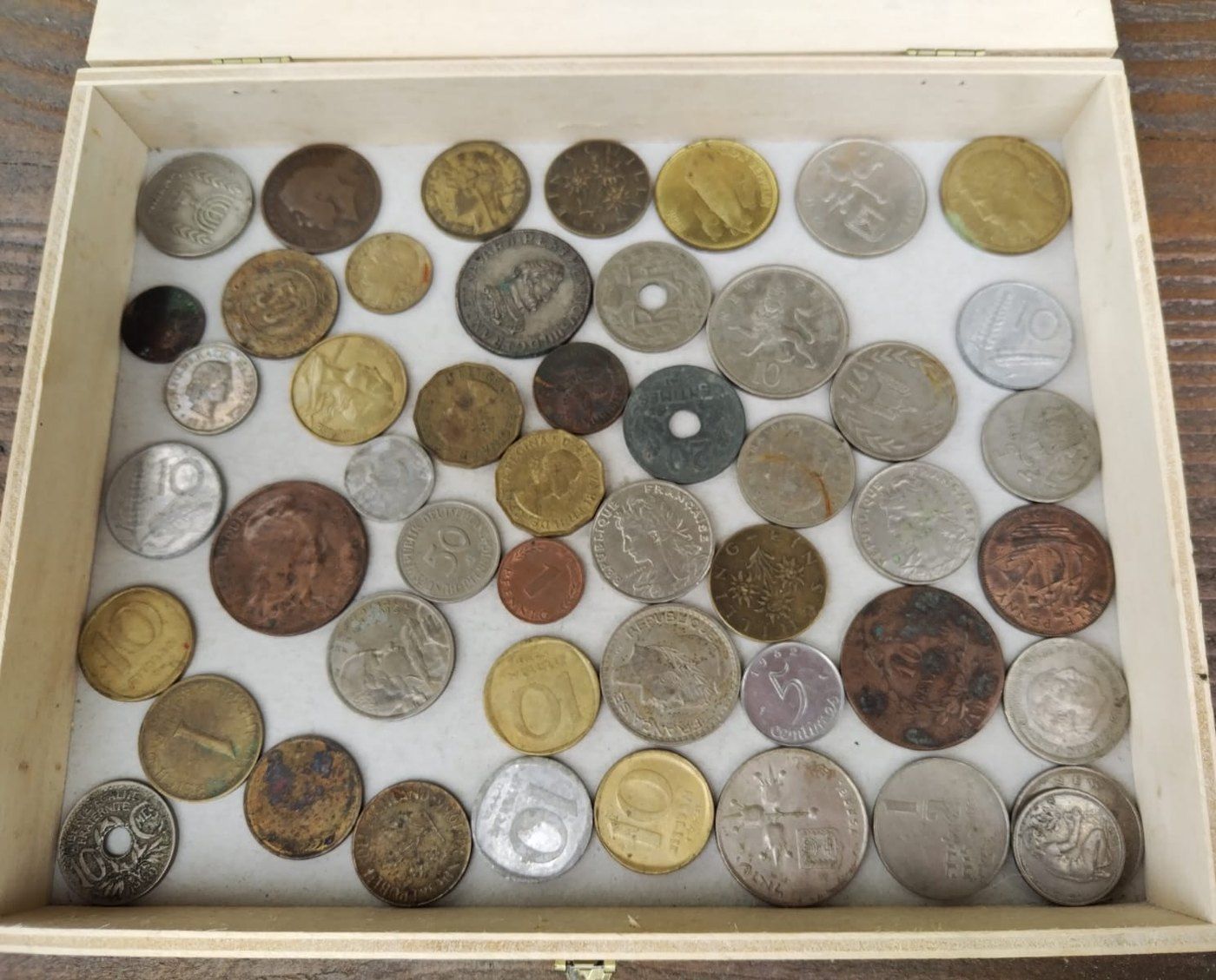 Coffret de bois rempli de pièces de monnaie de toutes tailles