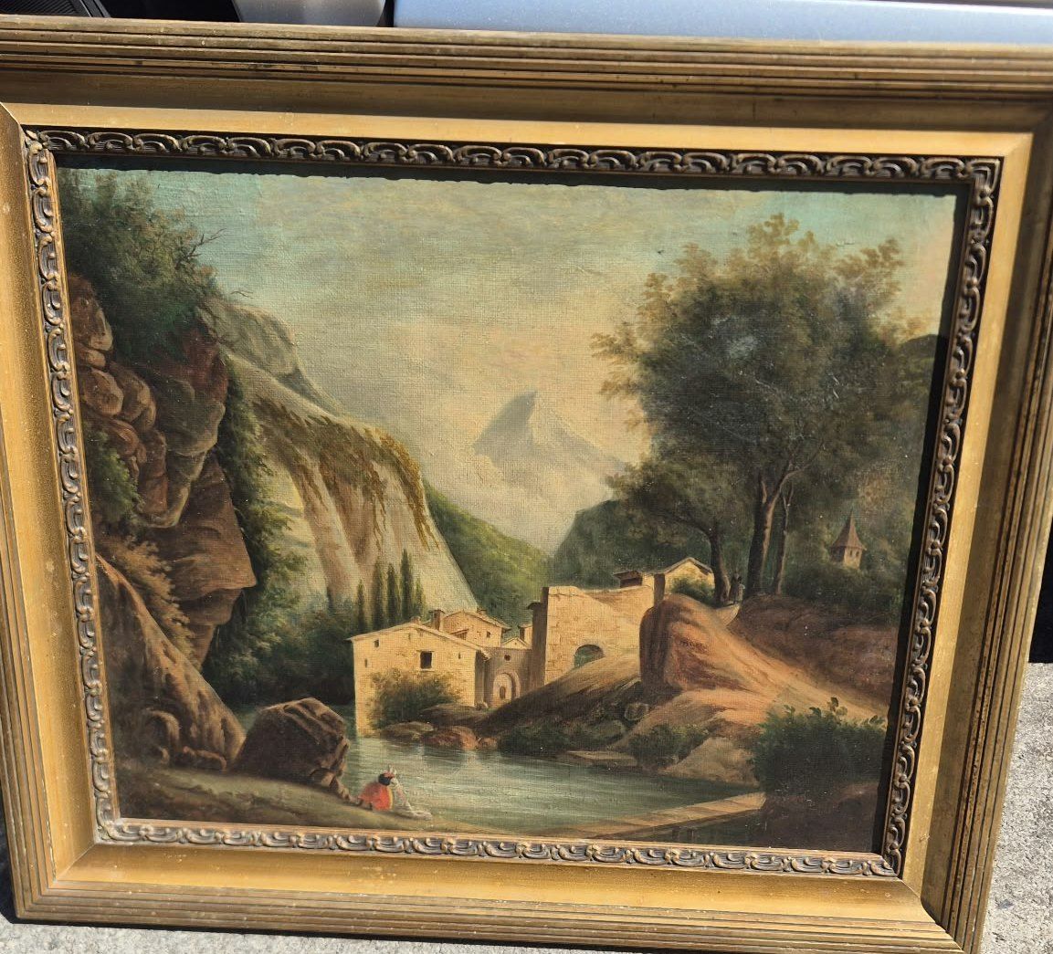 Tableau dans un cadre doré : paysage de montagne, maisons et rivière